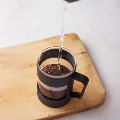 French Press Coffee Guide — Coffee Blooming in a French Press Coffee Blooming in a French Press on a Wooden Surface