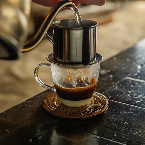 Vietnamese Coffee Filter with Condensed Milk at the Base of a Glass